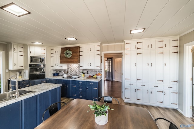 kitchen with sink, black appliances, white cabinets, blue cabinets, and light wood-type flooring