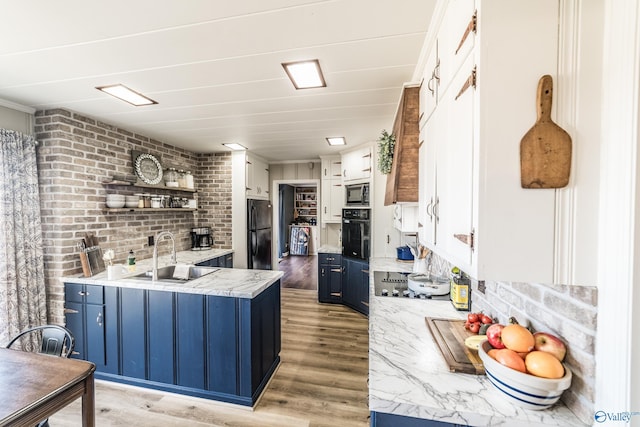 kitchen featuring blue cabinets, sink, white cabinets, black appliances, and light wood-type flooring