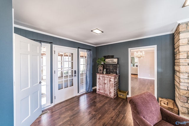 entryway with ornamental molding, dark hardwood / wood-style floors, and a notable chandelier