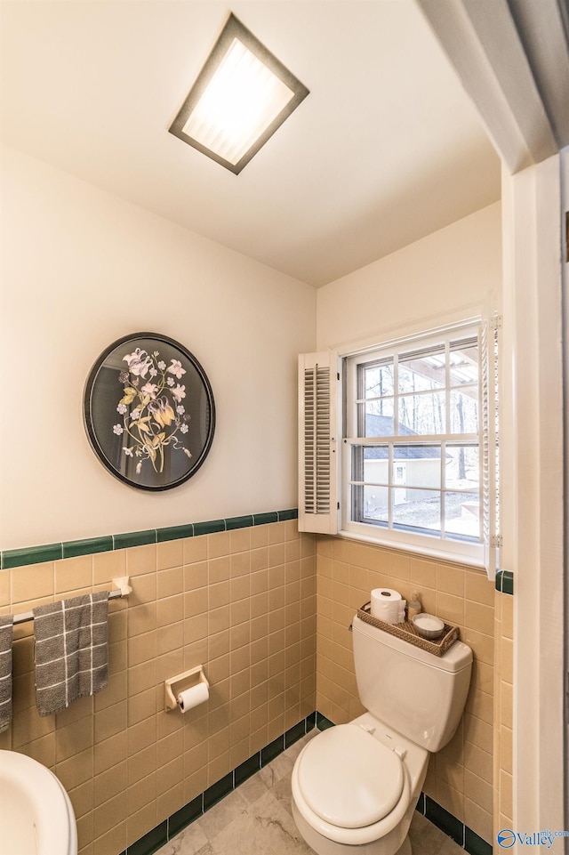 bathroom featuring toilet and tile walls