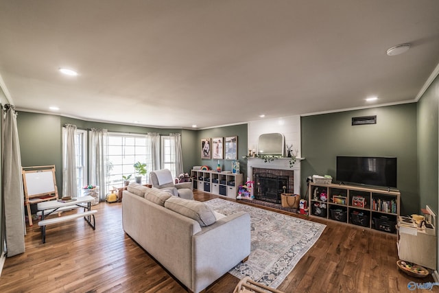 living room with hardwood / wood-style flooring, a fireplace, and ornamental molding