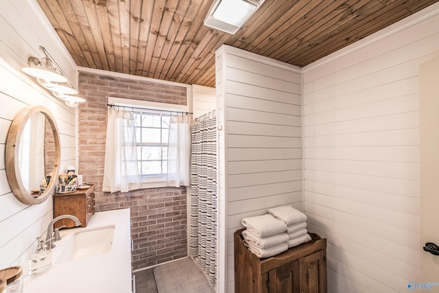 bathroom with wood ceiling, brick wall, and vanity