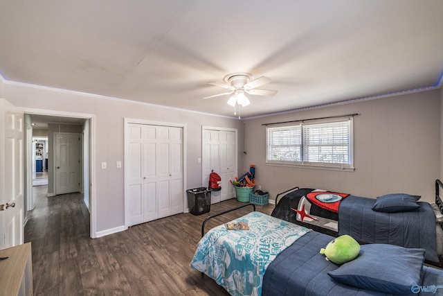 bedroom featuring multiple closets, ornamental molding, dark hardwood / wood-style floors, and ceiling fan