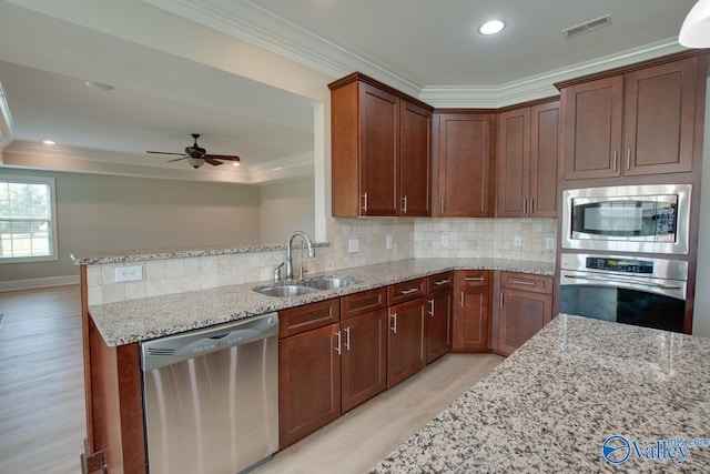 kitchen with ornamental molding, appliances with stainless steel finishes, light stone countertops, and sink