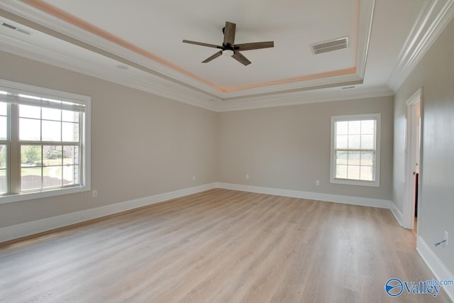 spare room featuring crown molding, light hardwood / wood-style flooring, ceiling fan, and a tray ceiling