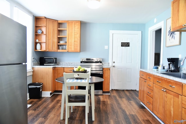 kitchen featuring light stone counters, sink, stainless steel appliances, and dark wood-type flooring