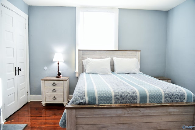 bedroom with dark hardwood / wood-style floors and a closet