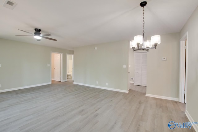 empty room with ceiling fan with notable chandelier and hardwood / wood-style floors