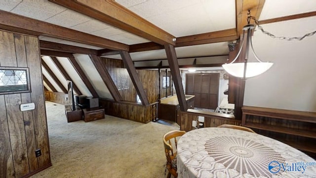 carpeted bedroom featuring beam ceiling, multiple windows, and wood walls