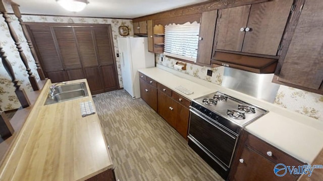 kitchen featuring dark brown cabinets, sink, white fridge, and range with electric stovetop