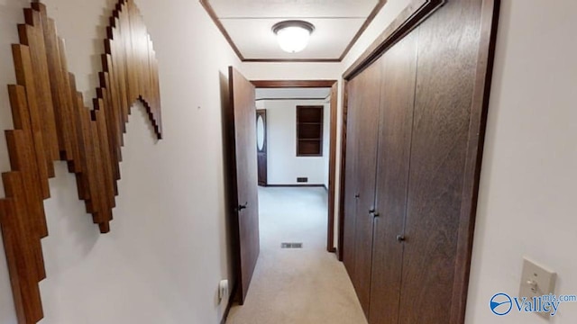 corridor with ornamental molding and light colored carpet