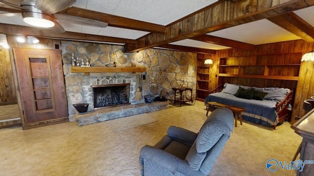 living room featuring beamed ceiling, wooden walls, a fireplace, and carpet flooring