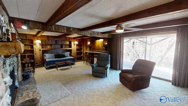 living room with light carpet, beamed ceiling, and wood walls