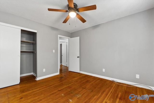 unfurnished bedroom featuring ceiling fan, a textured ceiling, a closet, and wood-type flooring