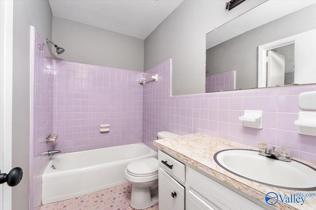 full bathroom with tile walls, vanity, a textured ceiling, toilet, and tiled shower / bath