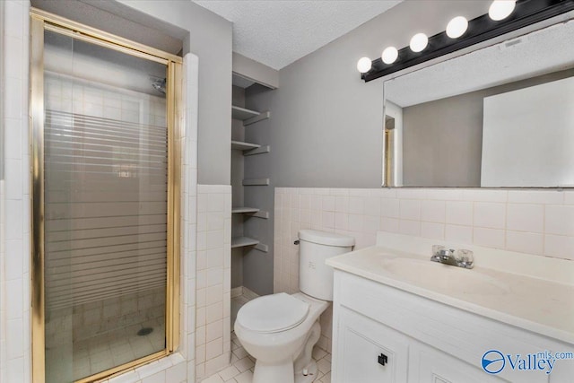 bathroom with tile patterned flooring, a textured ceiling, vanity, toilet, and tile walls