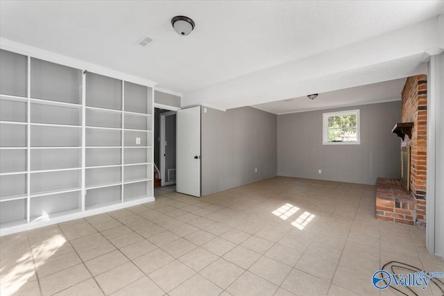 unfurnished living room featuring a brick fireplace and wood walls