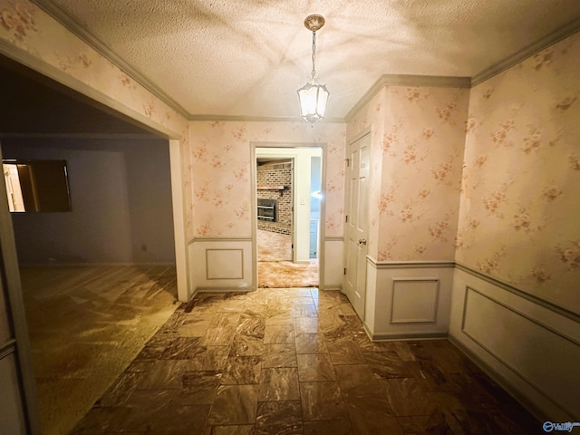 corridor with ornamental molding, a textured ceiling, and dark colored carpet