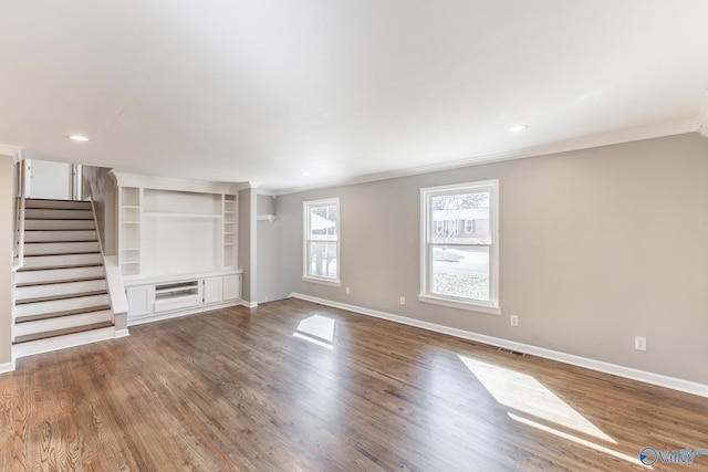 unfurnished living room featuring visible vents, stairs, baseboards, and wood finished floors