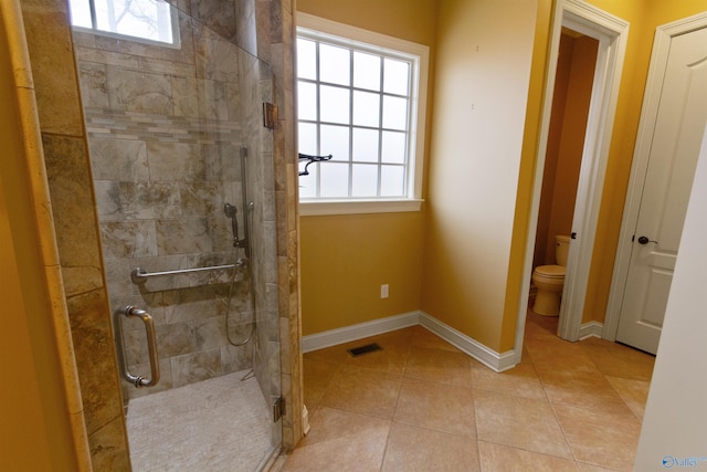 bathroom featuring tile patterned floors, plenty of natural light, a shower with shower door, and toilet