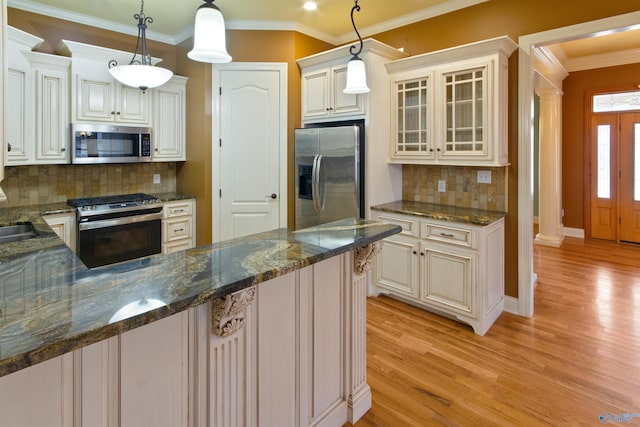 kitchen featuring dark stone countertops, stainless steel appliances, light hardwood / wood-style floors, decorative light fixtures, and ornate columns