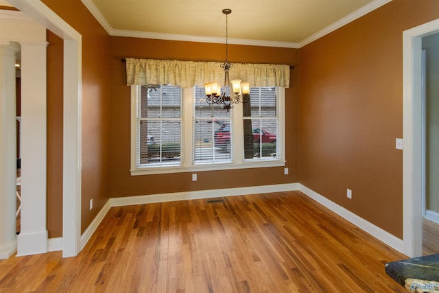 unfurnished dining area featuring hardwood / wood-style flooring, ornamental molding, decorative columns, and a notable chandelier