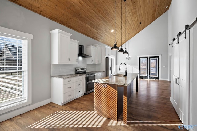 kitchen with a barn door, range with two ovens, wooden ceiling, wall chimney range hood, and a sink