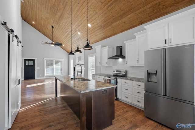 kitchen with a barn door, appliances with stainless steel finishes, wood ceiling, a sink, and wall chimney exhaust hood