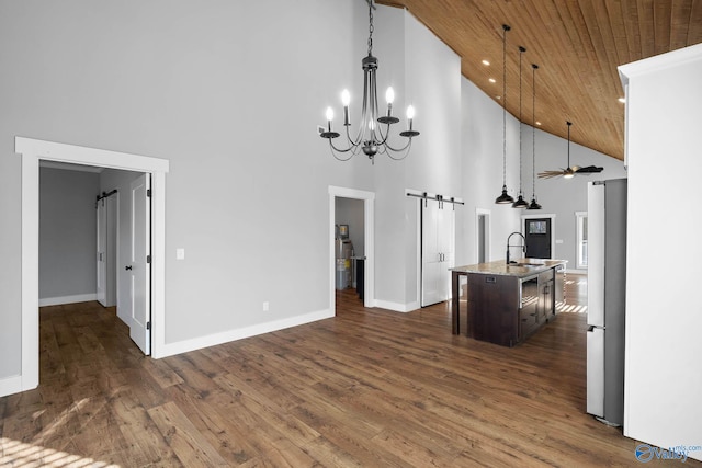 kitchen featuring a barn door, wooden ceiling, dark wood-style floors, freestanding refrigerator, and a sink