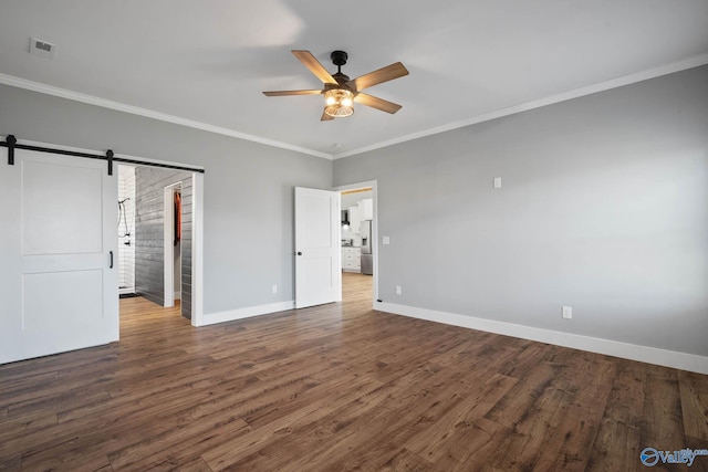 unfurnished bedroom with a barn door, baseboards, wood finished floors, and ornamental molding