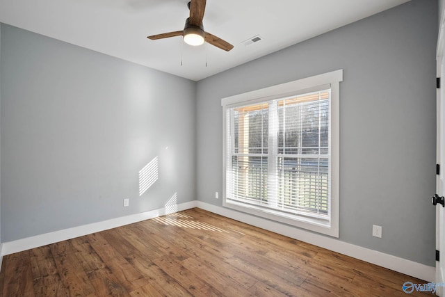 empty room featuring visible vents, ceiling fan, baseboards, and wood finished floors