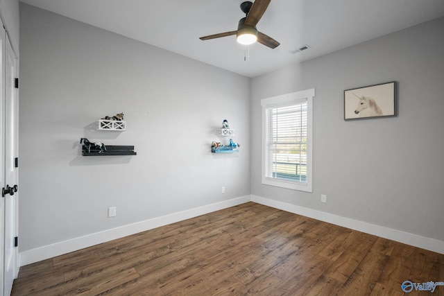 spare room featuring a ceiling fan, wood finished floors, visible vents, and baseboards