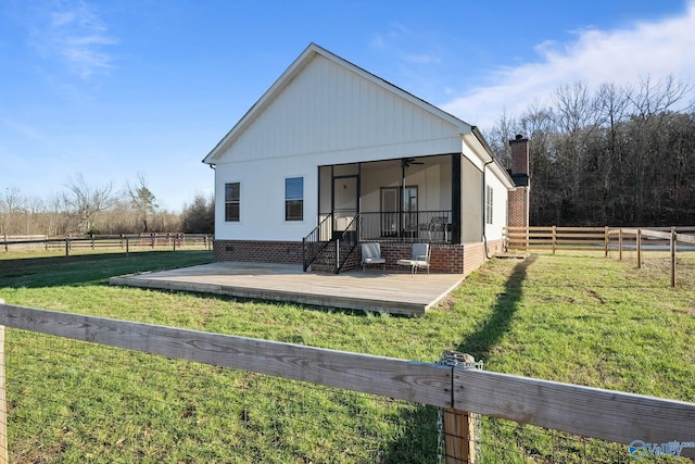 back of property featuring a lawn, a chimney, fence, and a ceiling fan