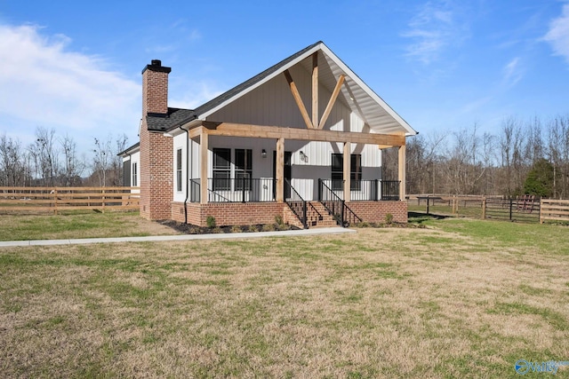 view of front facade with covered porch, a chimney, a front yard, and fence