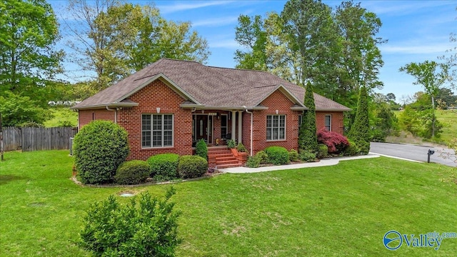 ranch-style home featuring brick siding, fence, and a front yard
