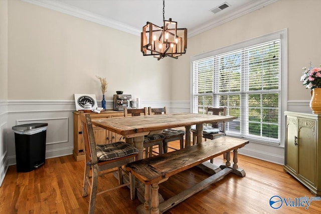 dining room featuring light wood finished floors, crown molding, and an inviting chandelier