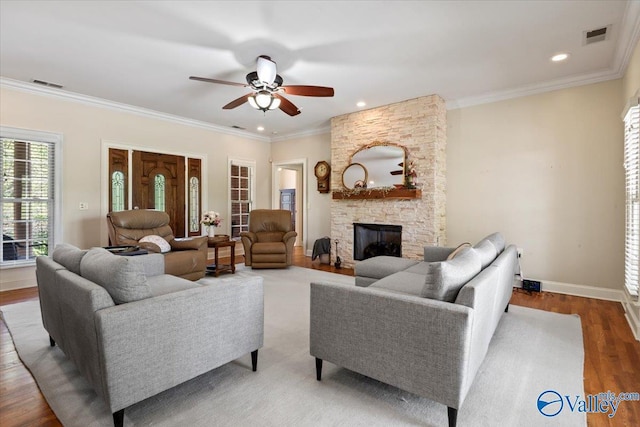 living area with wood finished floors, a stone fireplace, visible vents, and a ceiling fan