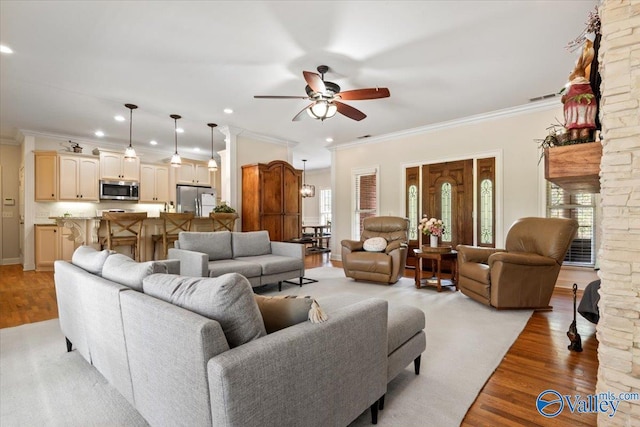 living room featuring a ceiling fan, visible vents, ornamental molding, and a healthy amount of sunlight