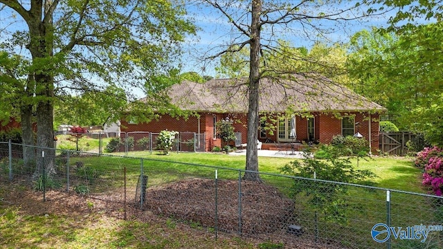 exterior space featuring a lawn, a fenced backyard, brick siding, and a patio area