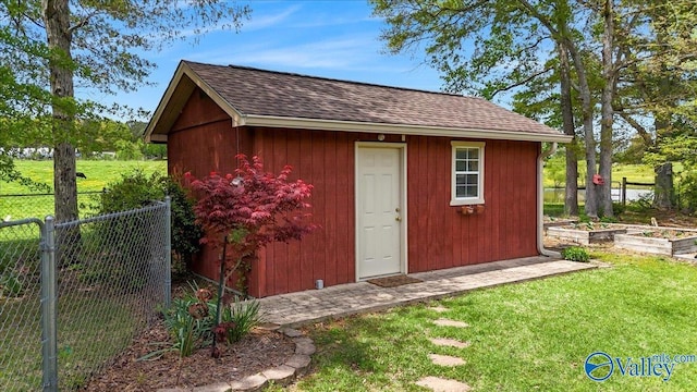 view of outbuilding featuring fence, an outbuilding, and a garden