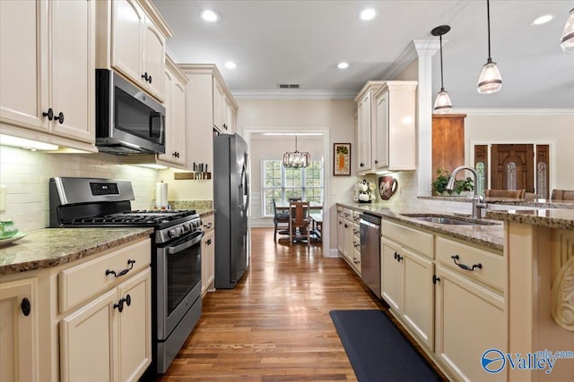 kitchen with a sink, visible vents, crown molding, appliances with stainless steel finishes, and cream cabinets
