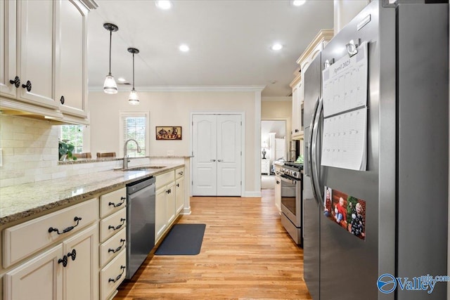 kitchen featuring tasteful backsplash, a sink, appliances with stainless steel finishes, light wood-style flooring, and ornamental molding