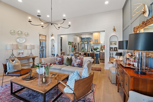 living room featuring a high ceiling, a chandelier, and light wood-type flooring