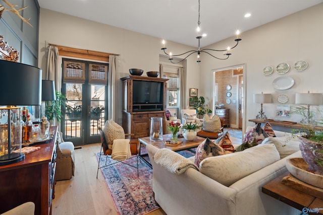 living room with french doors, an inviting chandelier, and light wood-type flooring