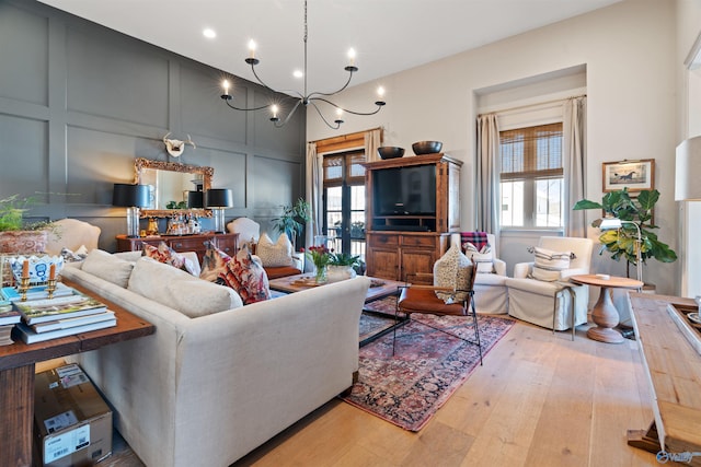 living room featuring light wood-type flooring, a wealth of natural light, and a chandelier