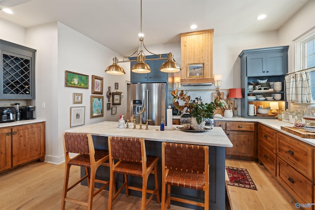 kitchen with decorative backsplash, high end appliances, hanging light fixtures, light hardwood / wood-style flooring, and a kitchen bar