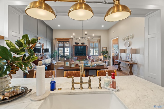 kitchen featuring light stone counters, pendant lighting, ornamental molding, sink, and hardwood / wood-style flooring