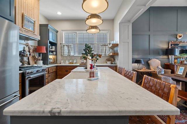 kitchen with light stone counters, gray cabinets, stainless steel appliances, and a kitchen island