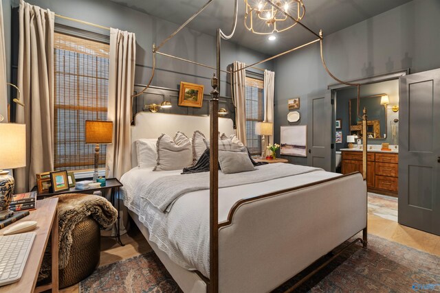 bedroom featuring ensuite bathroom, hardwood / wood-style floors, and an inviting chandelier