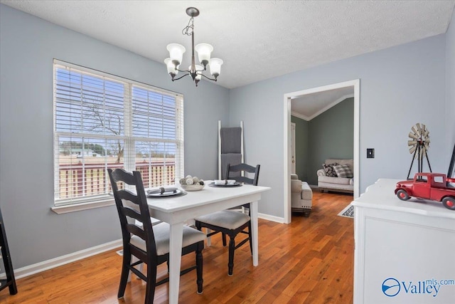 dining space featuring baseboards, a notable chandelier, wood finished floors, and a textured ceiling